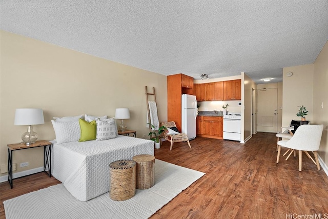 bedroom with dark wood-type flooring, white fridge, and a textured ceiling