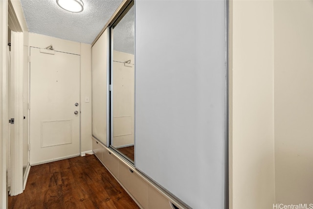 hallway with dark wood-type flooring and a textured ceiling