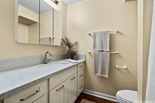 bathroom featuring vanity, hardwood / wood-style flooring, toilet, and a textured ceiling