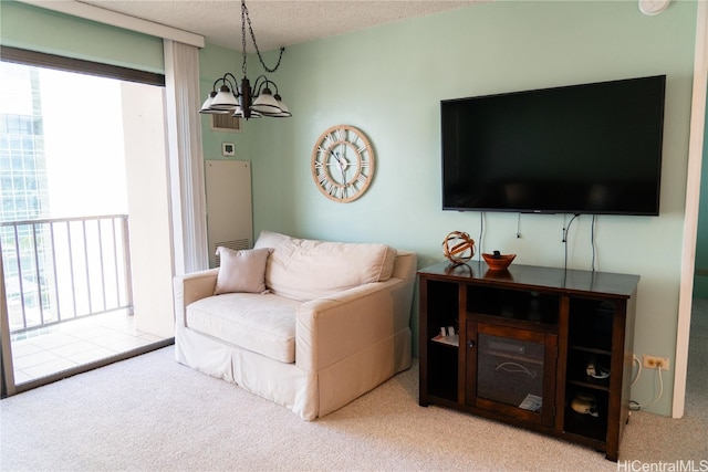 living room featuring a textured ceiling, a notable chandelier, and carpet floors