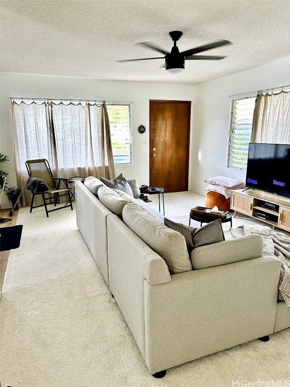 carpeted living room with a textured ceiling, plenty of natural light, and ceiling fan