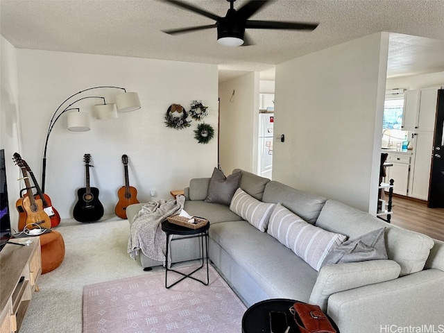 living room with ceiling fan, light carpet, and a textured ceiling