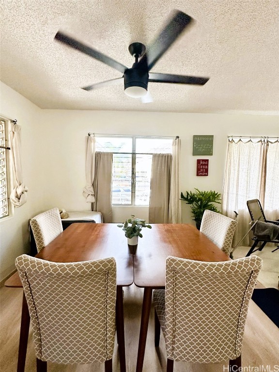 dining space featuring ceiling fan, light carpet, and a textured ceiling