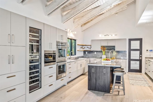 kitchen featuring a center island, sink, light hardwood / wood-style flooring, beam ceiling, and a kitchen bar