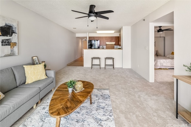 carpeted living room with a textured ceiling and ceiling fan