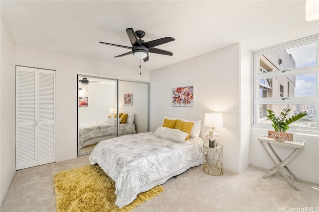 carpeted bedroom featuring a textured ceiling, multiple closets, and ceiling fan