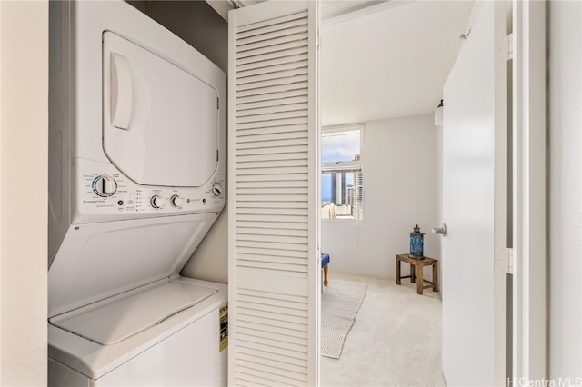 clothes washing area with stacked washer / drying machine and light colored carpet