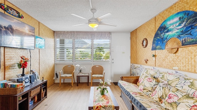 living area with a textured ceiling, light hardwood / wood-style floors, and ceiling fan