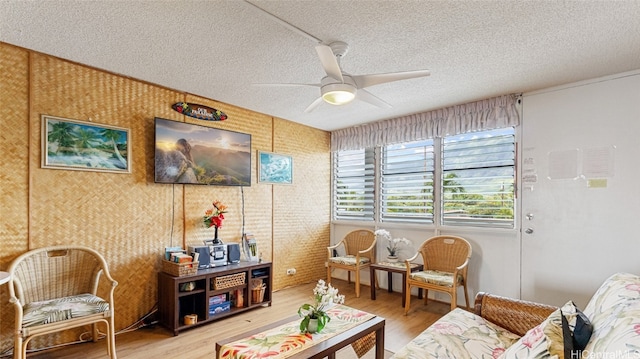 sitting room with a textured ceiling, hardwood / wood-style flooring, and ceiling fan