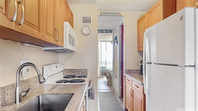 kitchen with sink, light tile patterned flooring, a textured ceiling, and white appliances