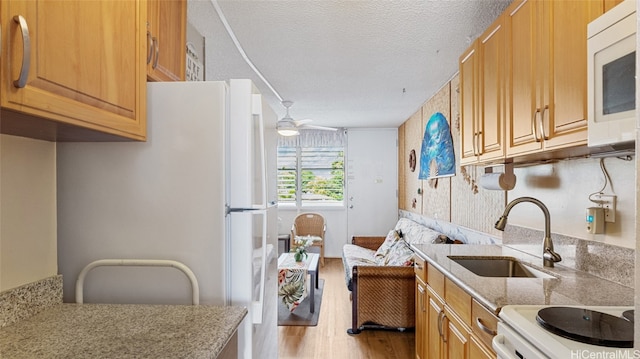 kitchen with light hardwood / wood-style flooring, sink, a textured ceiling, white appliances, and ceiling fan