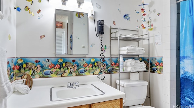 bathroom featuring tile walls, vanity, and toilet