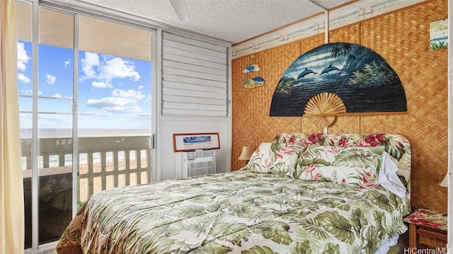 bedroom featuring a water view, multiple windows, access to outside, and a textured ceiling