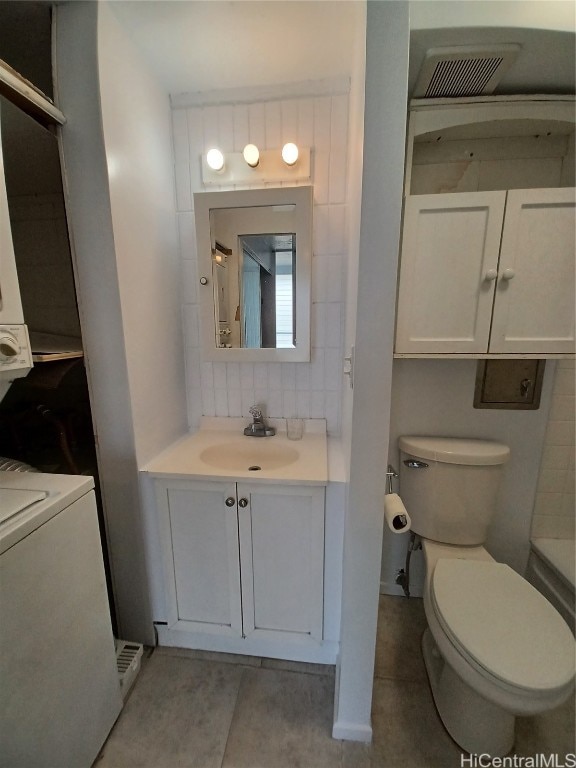 bathroom featuring tasteful backsplash, washer / clothes dryer, toilet, tile patterned floors, and vanity