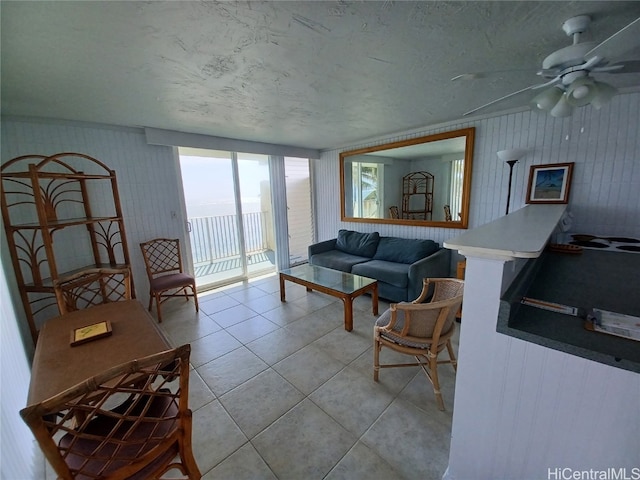 living room with light tile patterned flooring, a textured ceiling, and ceiling fan