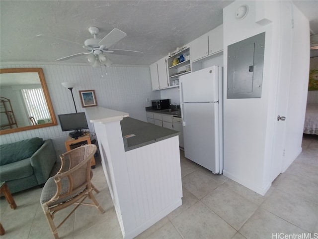 kitchen featuring white cabinets, electric panel, ceiling fan, wooden walls, and white appliances