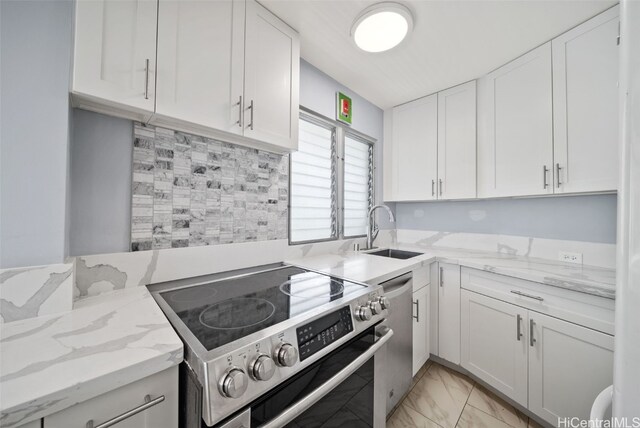 kitchen with white cabinets, light stone countertops, stainless steel appliances, and sink