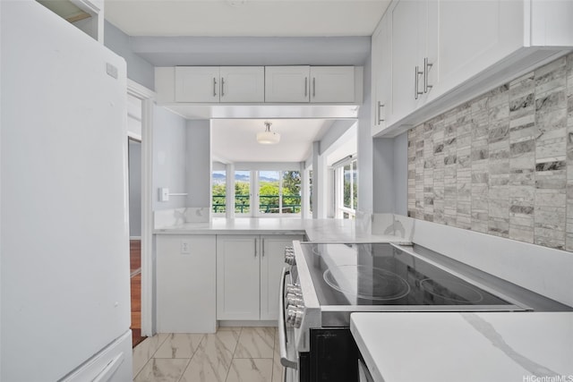 kitchen with white cabinets, marble finish floor, light countertops, freestanding refrigerator, and stainless steel electric stove