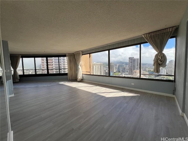 spare room with a wealth of natural light, hardwood / wood-style floors, and a textured ceiling