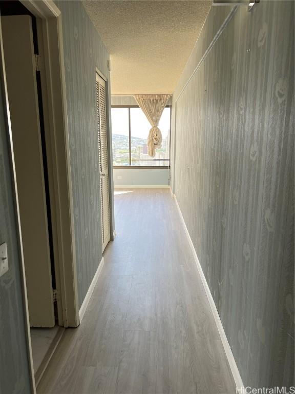 corridor with light hardwood / wood-style floors and a textured ceiling