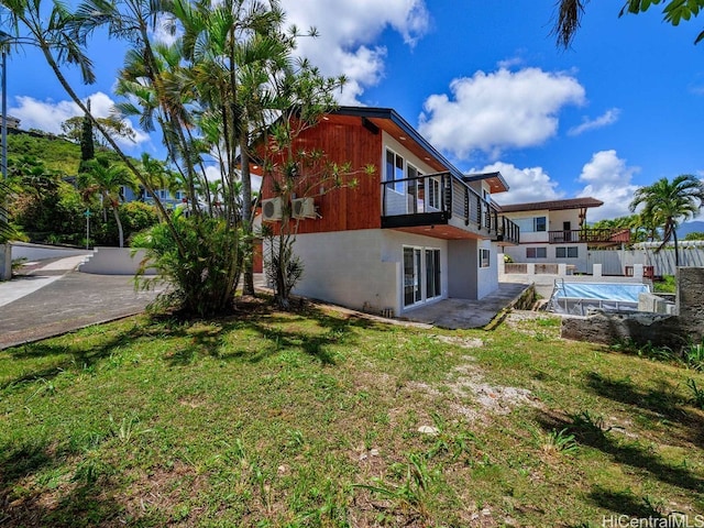 rear view of house featuring a patio, a lawn, and a balcony