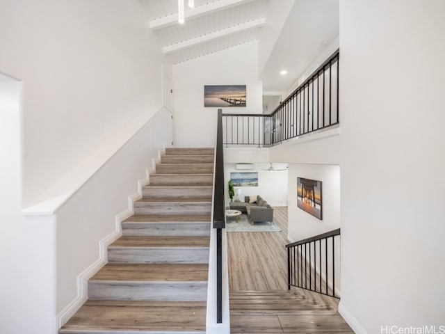 stairway with hardwood / wood-style flooring, high vaulted ceiling, and beamed ceiling