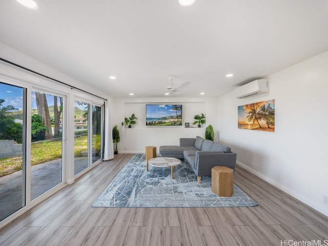 living room with light hardwood / wood-style flooring, a wall unit AC, and ceiling fan