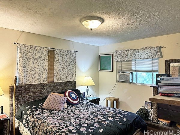 bedroom with cooling unit and a textured ceiling