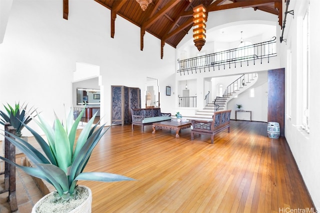 living room featuring beamed ceiling, hardwood / wood-style floors, a notable chandelier, and high vaulted ceiling