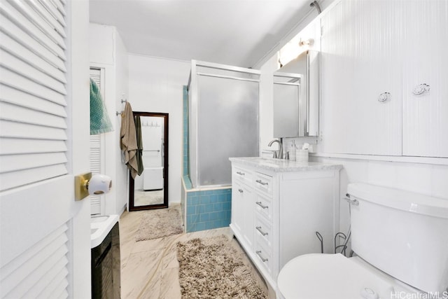 bathroom featuring vanity, a shower with shower door, and toilet