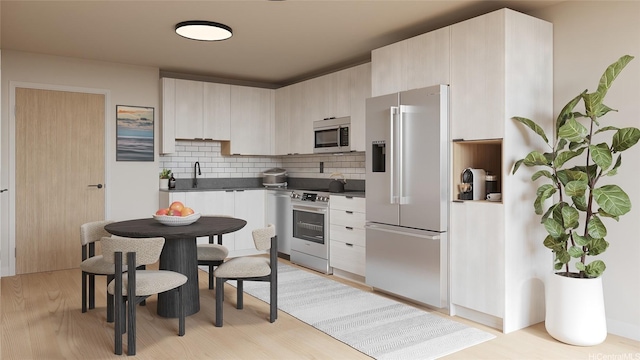 kitchen featuring light wood finished floors, stainless steel appliances, decorative backsplash, and dark countertops