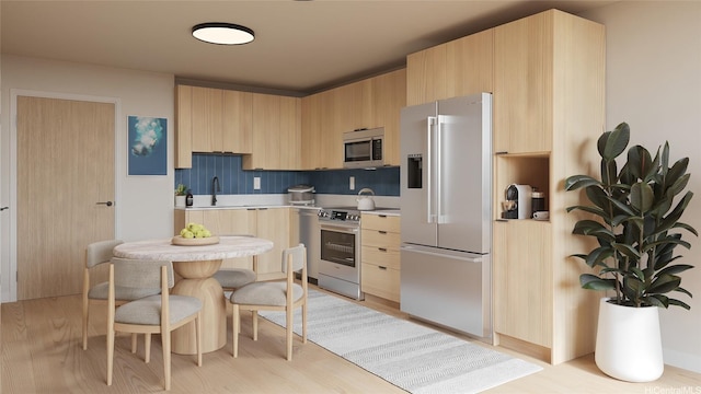 kitchen featuring light brown cabinetry, a sink, light wood-type flooring, light countertops, and appliances with stainless steel finishes