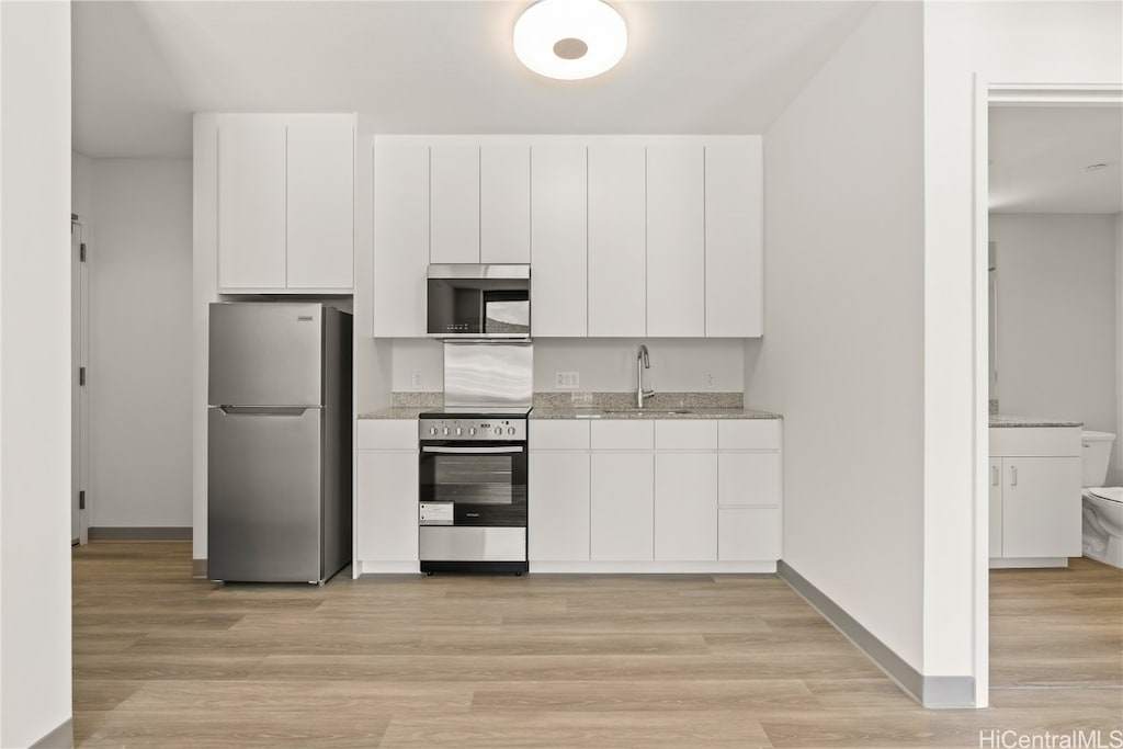 kitchen with sink, white cabinets, stainless steel appliances, and light wood-type flooring