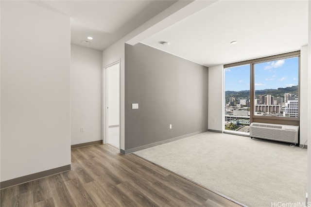 unfurnished room featuring a wall unit AC and hardwood / wood-style flooring