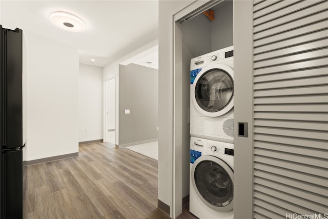 clothes washing area with stacked washing maching and dryer and hardwood / wood-style floors