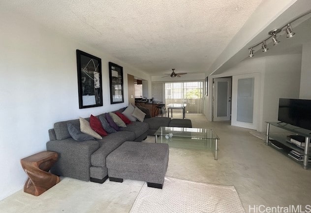 living room featuring rail lighting, ceiling fan, and a textured ceiling