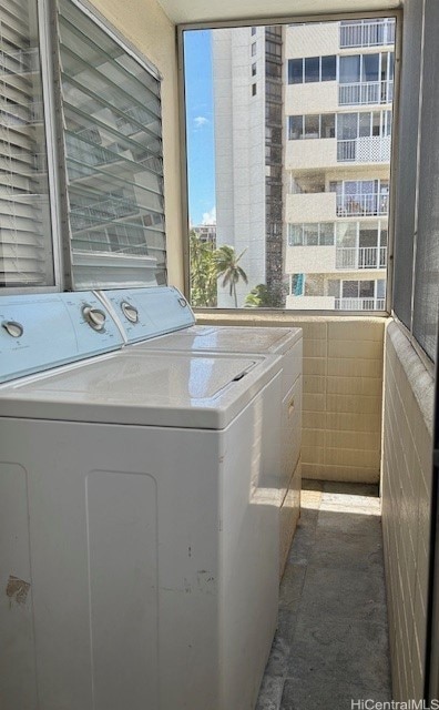 laundry room featuring tile walls and washing machine and clothes dryer