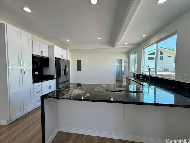 kitchen with white cabinets, appliances with stainless steel finishes, dark stone countertops, light hardwood / wood-style floors, and sink