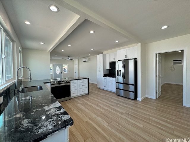 kitchen with appliances with stainless steel finishes, sink, light wood-type flooring, kitchen peninsula, and white cabinets