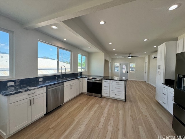 kitchen featuring appliances with stainless steel finishes, kitchen peninsula, white cabinets, and light hardwood / wood-style floors