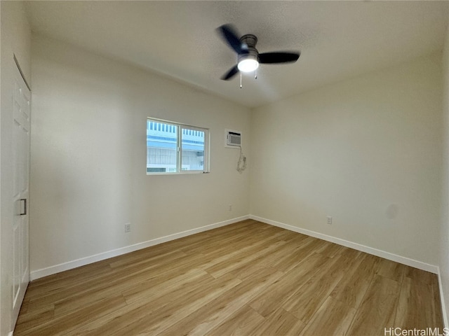 empty room with a wall unit AC, light wood-type flooring, and ceiling fan