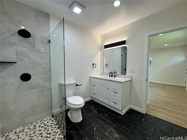 bathroom featuring vanity, hardwood / wood-style flooring, toilet, and a tile shower