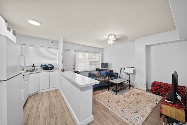 kitchen with kitchen peninsula, light wood-type flooring, white refrigerator, and white cabinets