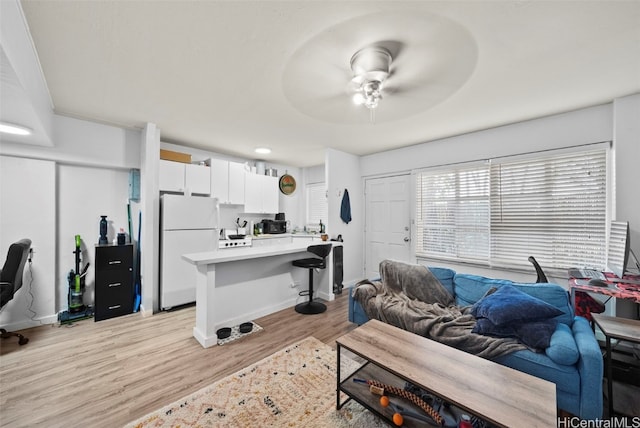 living room with light hardwood / wood-style flooring and ceiling fan