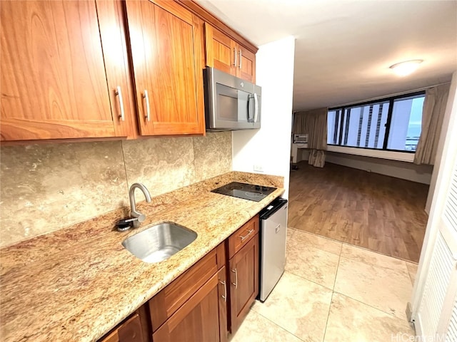 kitchen with decorative backsplash, light hardwood / wood-style flooring, stainless steel appliances, sink, and light stone counters