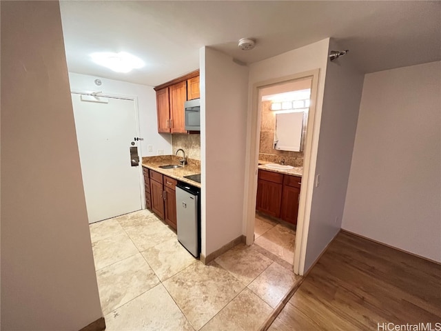 kitchen with sink, appliances with stainless steel finishes, light hardwood / wood-style floors, and tasteful backsplash