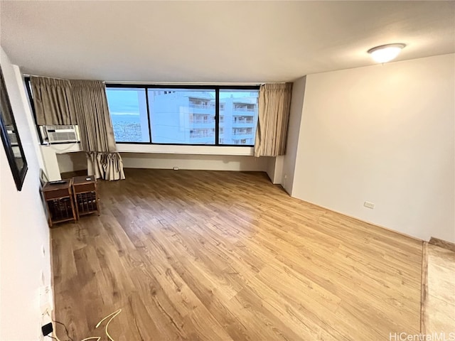 unfurnished living room featuring cooling unit and light wood-type flooring