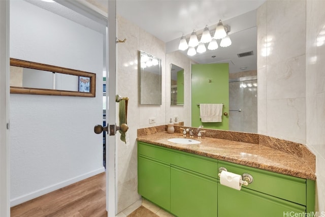 bathroom featuring vanity, wood-type flooring, and tiled shower