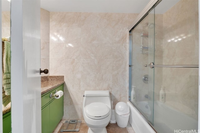 full bathroom featuring toilet, tile walls, bath / shower combo with glass door, vanity, and tile patterned flooring