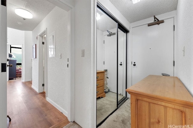 hall with light hardwood / wood-style flooring and a textured ceiling